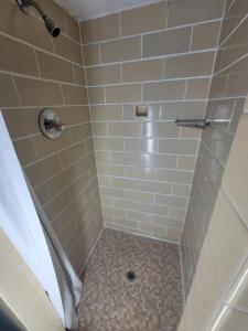 a bathroom with a shower with white tile at Medina Inn in Medina