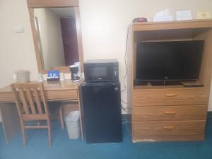 a room with a desk and a refrigerator and a television at Medina Inn in Medina