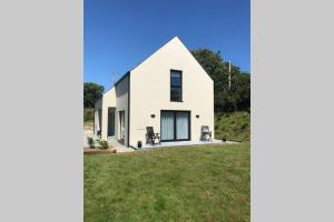 uma casa branca numa colina com um jardim verde em West Cork Escape em Clonakilty
