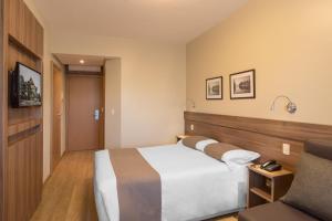 ein Hotelzimmer mit einem Bett und einem Stuhl in der Unterkunft Hotel Laghetto Viale in Gramado