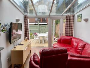 a living room with a red leather couch and a tv at Somers House - pet friendly & parking in Portsmouth