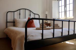 Schlafzimmer mit einem schwarzen Bett mit weißer Bettwäsche und Kissen in der Unterkunft Casas de Mar - Casa Coral in Olhão