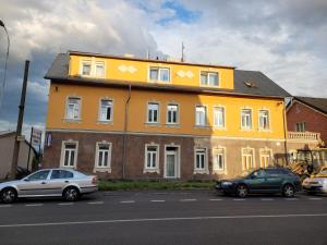 żółty budynek z samochodami zaparkowanymi przed nim w obiekcie Penzion Duong Apartments w Karlowych Warach