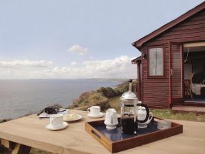 a table with a coffee maker on top of a deck with the water at Seagulls Nest in Cawsand