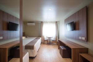 a room with two beds and a table and a window at Hotel Laghetto Viale in Gramado