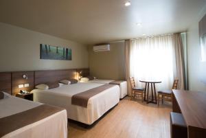 a hotel room with two beds and a table at Hotel Laghetto Viale in Gramado