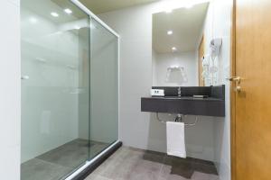 a bathroom with a sink and a glass shower at Hotel Laghetto Viale in Gramado