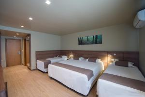 two beds in a hotel room with two beds at Hotel Laghetto Viale in Gramado