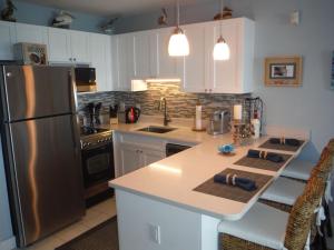 una cucina con frigorifero in acciaio inossidabile e armadietti bianchi di Luxury Sapphire Beach Resort and Marina 1BR VII a East End