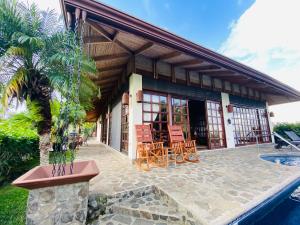 a house with a patio with chairs and a pool at Tropical Balinese Villa Atenas in Escobal