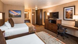 Habitación de hotel con 2 camas, escritorio y TV. en Best Western Plus Flathead Lake Inn and Suites, en Kalispell