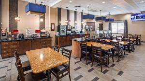 a restaurant with tables and chairs and a bar at Best Western Plus Williston Hotel & Suites in Williston