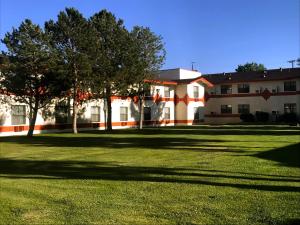 a building with trees in front of a grass field at NavajoLand Hotel in Tuba City