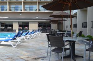 a row of chairs and tables with umbrellas next to a pool at Coast Capri Hotel in Kelowna