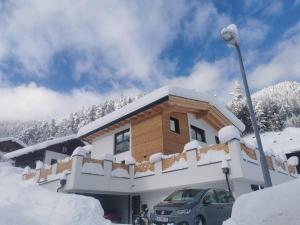 une maison recouverte de neige avec une voiture garée devant dans l'établissement Appartement Grafoner, à Sankt Anton am Arlberg