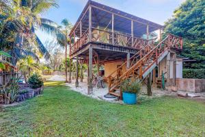 ein Haus mit einer Holzterrasse und einem Rasenplatz in der Unterkunft Three Little Birds in Caye Caulker