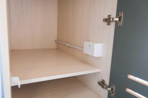 a small locker room with a shelf and a lightswitch at Hotel Give in Christchurch