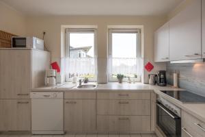a kitchen with white cabinets and a sink at Hafenflair in Husum