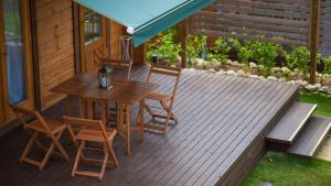eine Holzterrasse mit einem Tisch und Stühlen auf einem Haus in der Unterkunft ロガシス石垣野底ヴィラ in Ibaruma