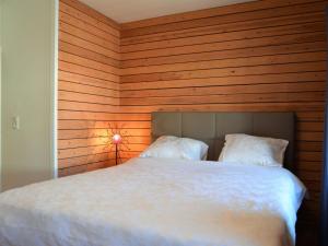 a bedroom with a white bed with a wooden wall at Cozy home with view and hottub in Rochehaut