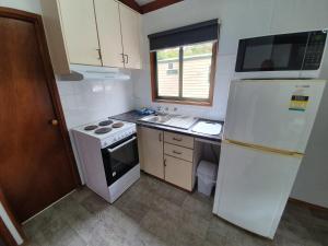 a kitchen with a stove, refrigerator and sink at G'Day Parks Ararat - formerly Pyrenees Caravan Park in Ararat