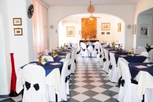 a row of tables in a room with blue and white chairs at Hotel Belsole in Ischia