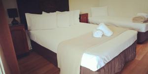 2 Betten in einem Hotelzimmer mit weißer Bettwäsche in der Unterkunft Country Plaza Motor Inn in Mackay