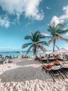 una playa con sillas, palmeras y el océano en Papagayo Hotel Boutique, en Playa del Carmen
