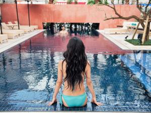 una mujer sentada en el agua en una piscina en Hotel Palm Royal Naha Kokusai Street, en Naha