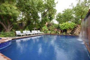 a large swimming pool with white chairs in a yard at Mandore Guest House in Jodhpur