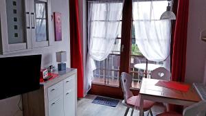 eine Küche mit einem Tisch und einem Fenster mit roten Vorhängen in der Unterkunft Ferienwohnung Sweety Haus Sachsensteinblick in Bad Sachsa