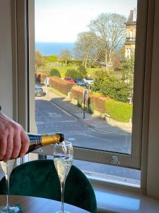 a person pouring a glass of wine in front of a window at Stylish apartment with free parking, lift & views in Scarborough