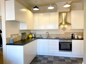 a kitchen with white cabinets and a sink at Stylish apartment with free parking, lift & views in Scarborough