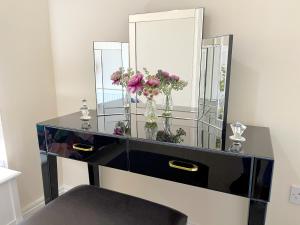 a dresser with a mirror and flowers in it at Stylish apartment with free parking, lift & views in Scarborough