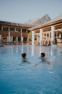 two people are swimming in a swimming pool at G'sund & Natur Hotel Die Wasnerin - Adults Only in Bad Aussee