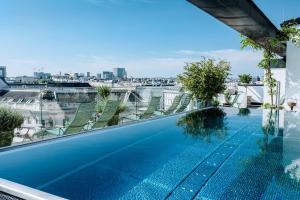 a swimming pool on the roof of a building with chairs at Grand Ferdinand Vienna – Your Hotel In The City Center in Vienna