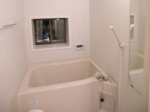 a bathroom with a bath tub and a window at Guesthouse HANA Nishijin in Kyoto