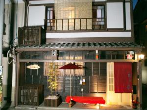 Guesthouse HANA Nishijin في كيوتو: مبنى بطاوله ومقعد احمر
