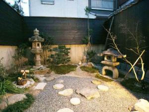 a garden with a lantern and a birdbath and a fountain at Guesthouse HANA Nishijin in Kyoto