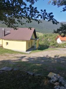 ein gelbes Haus mit rotem Dach in der Unterkunft Apartman Juka in Krasno Polje
