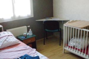 sypialnia z łóżeczkiem dziecięcym, stołem i biurkiem w obiekcie Chambre chez l'habitant w mieście Valence