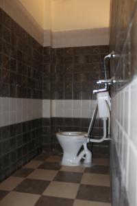 a bathroom with a toilet and a tiled wall at Mother Hostel in Varanasi