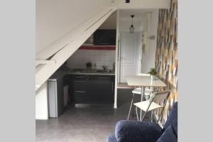 uma cozinha com uma mesa e uma cozinha debaixo de uma escada em Appart Cosy Annœullin - Proche toutes commodités em Annoeullin