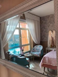 a mirror reflecting a bedroom with a bed and a window at B-LBAIT KAEC Honeymoon Style for family in King Abdullah Economic City