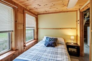 a bed in a room with wooden walls and windows at Chandler Hill Base Camp - Enjoy A Nature Getaway in this Rustic Home in the Mountains, 10 minutes from Sunday River Ski Mountain! home in Bethel