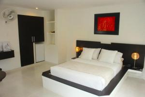 een slaapkamer met een wit bed en een rood schilderij aan de muur bij Hotel Sierra de la Cruz in Valle de San José