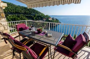 balcón con mesa, sillas y vistas al océano en Indy's Beach Apartments en Dubrovnik