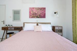 a bedroom with a large bed with a pink blanket at Stenorimi Valley House - Livadi, Astypalea in Livadi Astypalaias