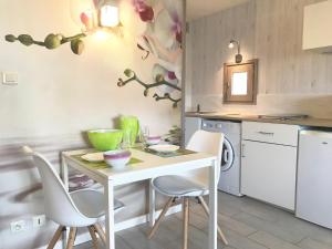 eine Küche mit einem Tisch, 2 Stühlen und einem Waschbecken in der Unterkunft Studio Les Remparts de Kerjouanno in Arzon