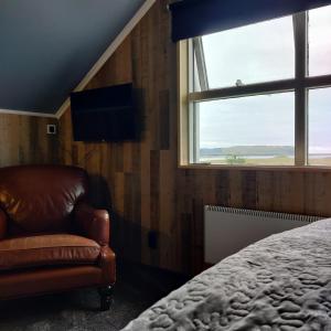 a room with a bed, chair and a window at Prestshús 2 Guesthouse in Vík